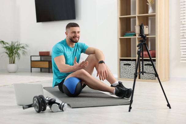Trainer with ball streaming online fitness lesson on phone at home - Foto, Imagem