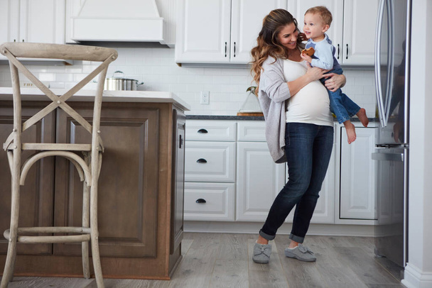 Mikään ei ole niin ihanaa kuin olla äiti. raskaana oleva nainen ja hänen poikansa viettävät aikaa yhdessä keittiössä kotona - Valokuva, kuva