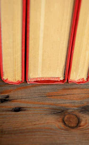 Kręgosłupy książek z czerwoną okładką. Trzy książki stoją obok siebie na drewnianym stole. Koniec książki to gęste arkusze zamkniętej książki.. - Zdjęcie, obraz