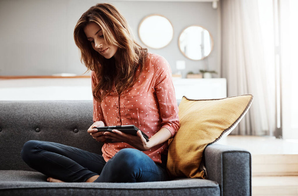 Socializar desde el sofá. una joven atractiva usando una tableta digital en el sofá en casa - Foto, Imagen