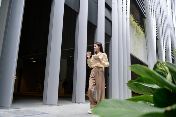 A young businesswoman is working in modern city downtown of Singapore  - Фото, изображение
