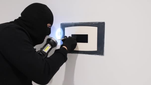 Un carterista masculino con una máscara negra abre una caja fuerte usando herramientas. Violación de la ley. - Imágenes, Vídeo