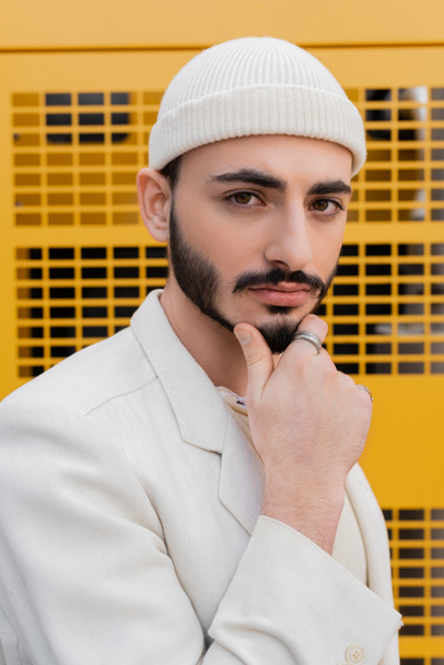 portret van stijlvolle gay man in beige hoed kijken naar camera buiten  - Foto, afbeelding