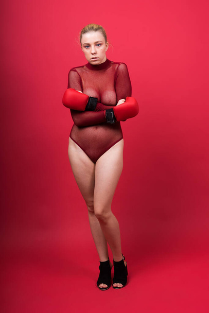 Seductive young and fit female fighter posing in gloves in a studio - Foto, Imagem