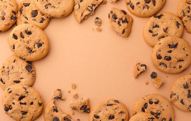 Frame made of many delicious chocolate chip cookies on beige background, flat lay. Space for text - 写真・画像