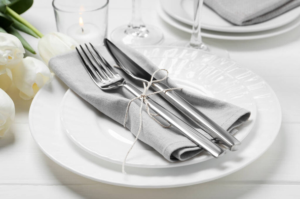 Stylish setting with cutlery, burning candle and tulips on white wooden table - Valokuva, kuva