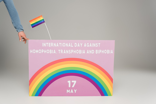 Widok geja w pobliżu plakatu z Międzynarodowym Dniem Walki z Homofobią, Transpfobią i Bifobią na szarym  - Zdjęcie, obraz