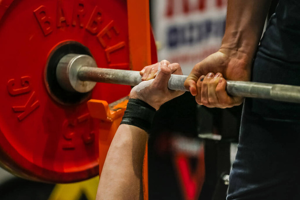 arm powerlifter in wrist wraps to hold heavy barbell before bench press powerlifting competition - Foto, Imagen