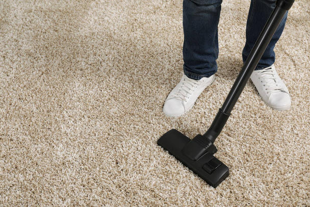 Man cleaning carpet with vacuum cleaner at home, closeup. Space for text - Fotó, kép