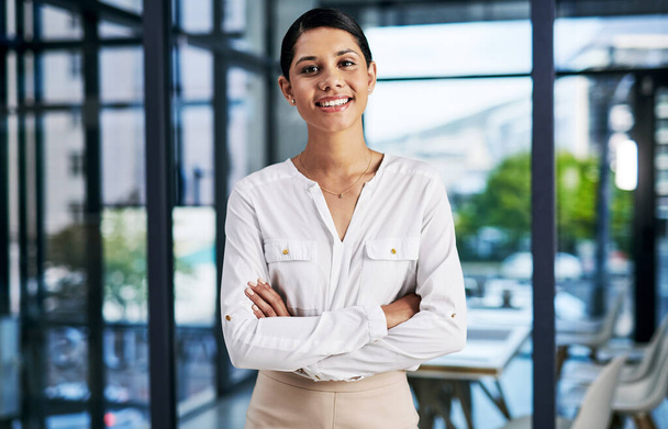 Choosing corporate was the best decision ever. Cropped portrait of an attractive young businesswoman smiling while standing with her arms folded in a modern office - Zdjęcie, obraz