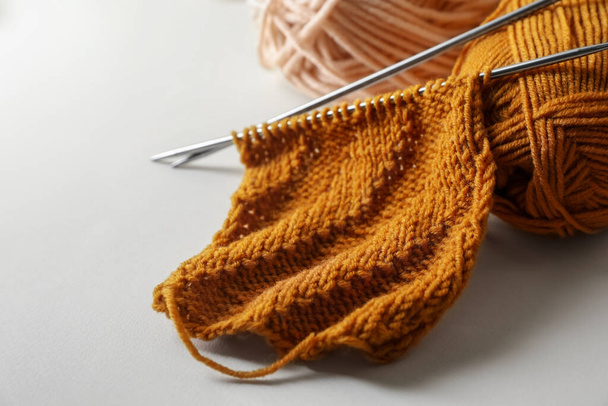 Soft orange knitting, colorful yarns and metal needles on beige background, closeup - Fotó, kép