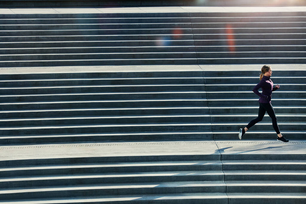 Youve got more than you think. Full length shot of an attractive young sportswoman running up and down stairs outside - Fotografie, Obrázek