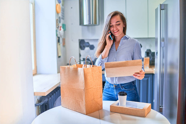Modern busy casual cute adult happy smiling young woman customer received cardboard bags with takeaway food and drinks at home. Fast delivery service concept - Fotoğraf, Görsel