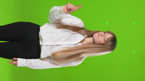 Front view of pretty, emotional lady standing in studio, raising hand, showing no. Attractive, young woman looking at camera, denying. Isolated on green studio background. - Footage, Video