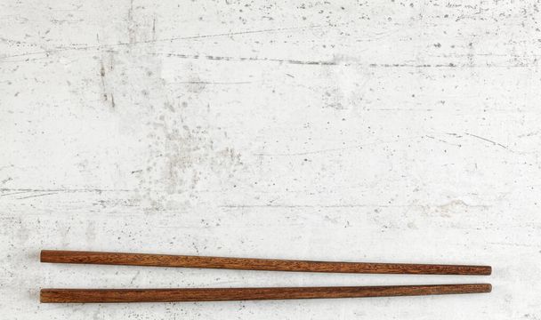 Flat lay photo - pair of dark wood chopsticks on white board. Wide banner for Asian or Chinese food, space for text above - Фото, зображення