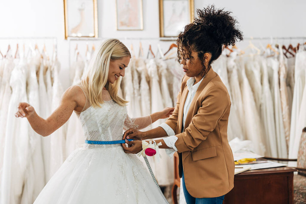 Tailor is measuring waist circumference on a bride in a wedding dress - Фото, зображення