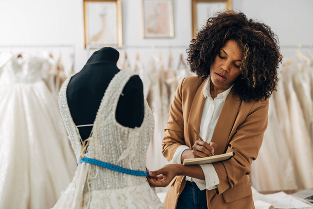 A multiracial tailor works in a bridal salon and designs wedding dress - Фото, зображення