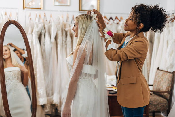 An assistant is putting a veil on a happy brides head - Фото, зображення