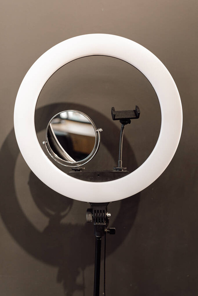Gros plan de l'anneau lampe LED avec support de téléphone, miroir pour la beauté professionnelle blogging vlog enregistrement en continu sur fond gris. Tutoriel maquillage, selfie, technologie, photographie, Youtube. Vertical. - Photo, image
