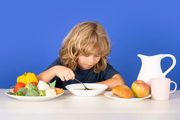 Child eating soup. Adorable little boy eating vegetable soup. Cute kid and healthy food, organic vegan soup with vegetables - Fotografie, Obrázek