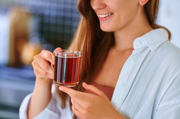 Happy beautiful joyful carefree satisfied attractive woman drinking hot black tea at home kitchen - Фото, зображення