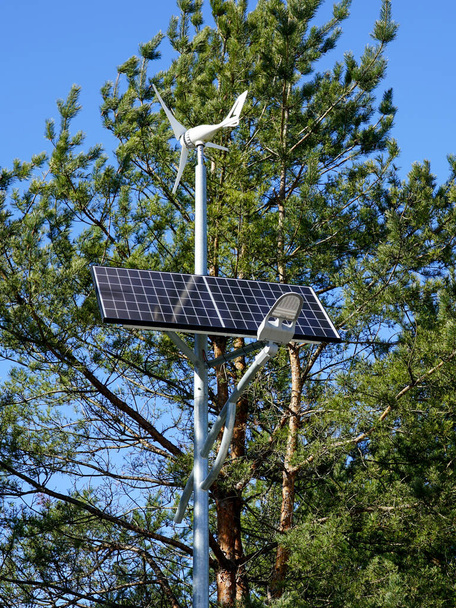 Palo con innovativo lampione a LED alimentato da pannello di celle solari e piccolo generatore di elettricità eolica, sfondo cielo blu - Foto, immagini
