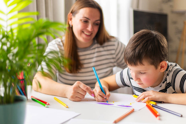 家の机に座っている鉛筆で母と子供の絵。幸せな家族 - 写真・画像