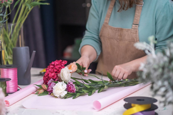 Decoradora de flores experta usando sus manos para crear un hermoso ramo de rosas rosadas de cerca. tienda más lenta - Foto, imagen