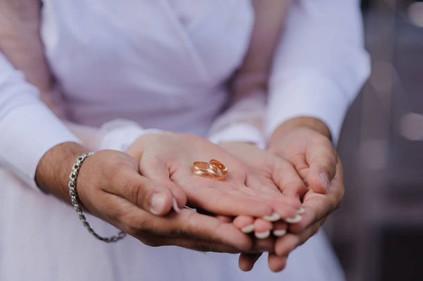 Βέρες στα χέρια των νεόνυμφων. Χρυσά δαχτυλίδια στο χέρι ενός άντρα και μιας γυναίκας - Φωτογραφία, εικόνα
