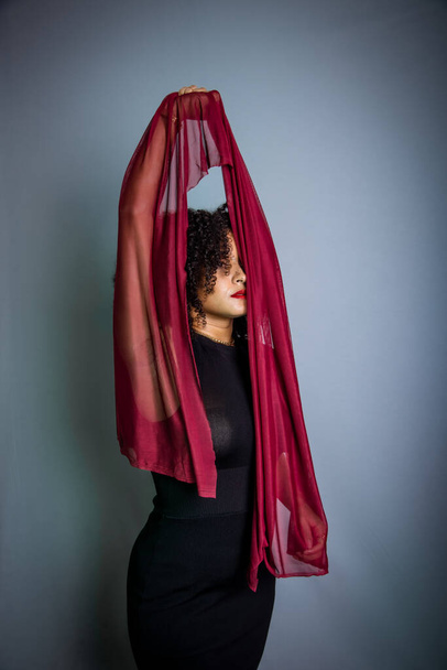 Schöne junge Frau mit rotem Tuch, das um ihren Körper hängt. Studioporträt - Foto, Bild