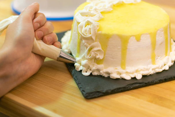 Hands decorating and preparing lemon cake. Concept of homemade and professional pastry. - Фото, зображення