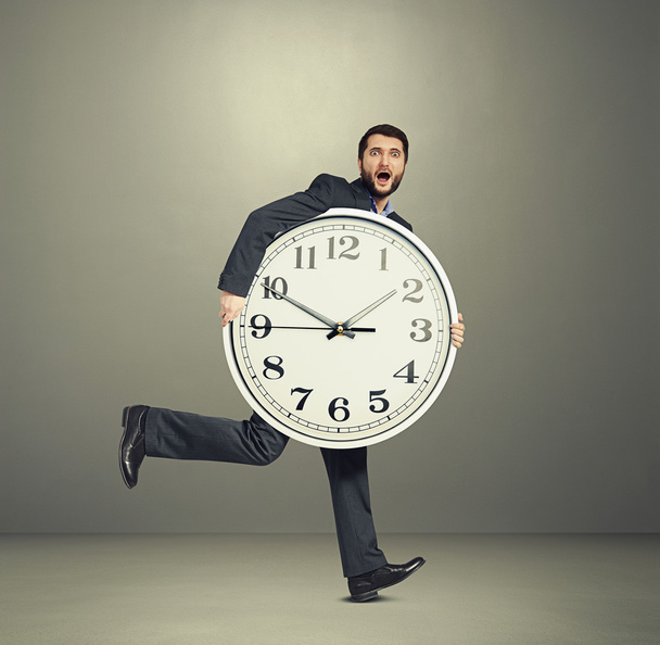 hombre sosteniendo gran reloj y corriendo
 - Foto, Imagen