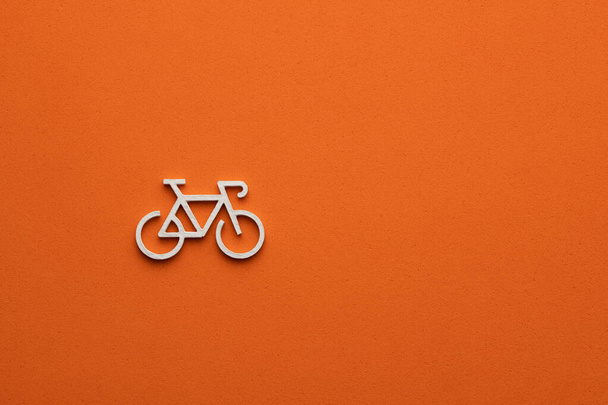 White bicycle on orange colored background - bicycle symbol for web site design or logo - Photo, image