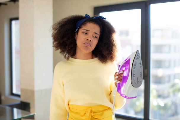 pretty afro black woman feeling sad and whiney with an unhappy look and crying. iron clothes laundry concept - Foto, Imagen
