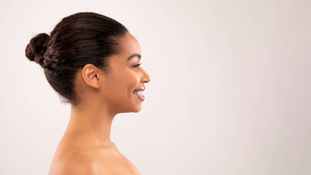 profile portrait of smiling beautiful half-naked millennial black woman looking at copy space for advertisement over colorful studio background, banner for skin care routine, spa, massage treatment - Photo, Image