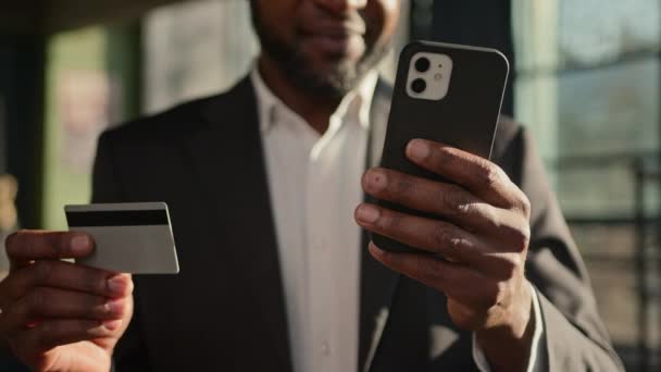 Κοντινό πλάνο πιστωτική κάρτα άγνωστης Αφρικής Αμερικανός ενήλικας επιχειρηματίας τραπεζίτης στο γραφείο πληρώσει online στο κινητό τηλέφωνο χρήματα που πληρώνουν ηλεκτρονικό εμπόριο ψώνια εισάγετε ασφαλή κωδικό ασφαλή συναλλαγή πληρωμής - Πλάνα, βίντεο