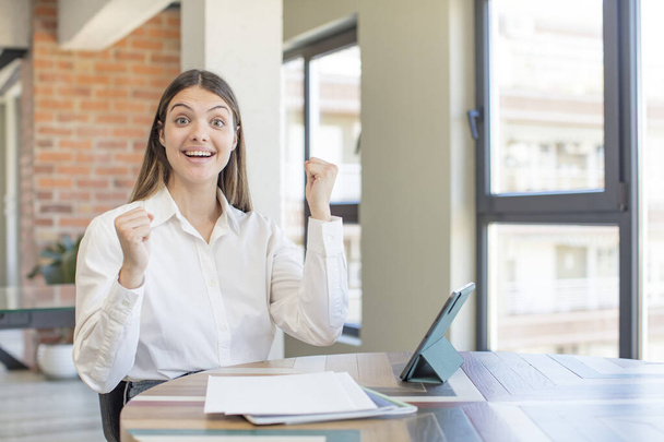 young pretty woman feeling shocked,laughing and celebrating success. telecommuting concept - Fotoğraf, Görsel