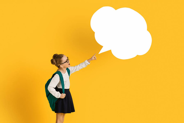 Look There. Cute Little Schoolgirl Pointing At Empty Speech Bubble With Finger, Excited Preteen Female Pupil Demonstrating Copy Space While Standing Over Yellow Studio Background, Collage - Photo, Image