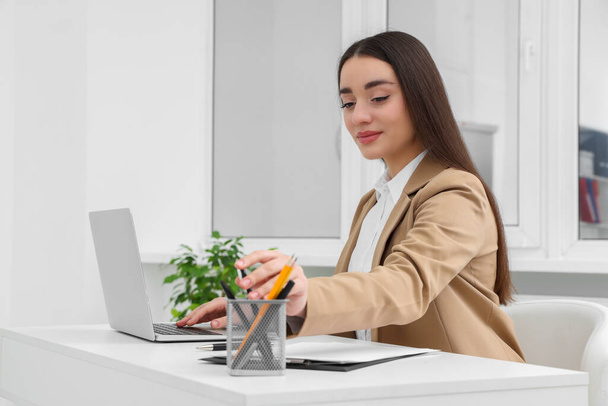 Young female intern working with laptop at table in office - Φωτογραφία, εικόνα