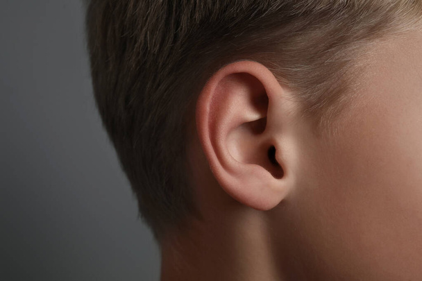 Boy on grey background, closeup of ear - Zdjęcie, obraz