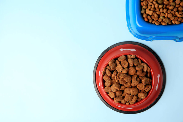 Dry pet food in feeding bowls on light blue background, flat lay. Space for text - Valokuva, kuva