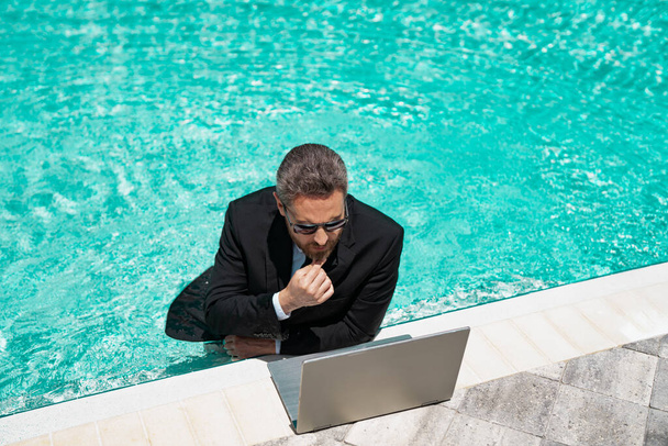 busy businessman has freelance business online. businessman has freelance business in swimming pool. businessman has freelance business with laptop. photo of businessman has freelance business in pool - Photo, Image