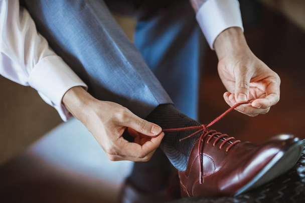 Hombres guapos atando sus elegantes cordones de zapatos. La aparición de un hombre de negocios. Detalles del traje y el aspecto general. Foto de alta calidad - Foto, Imagen