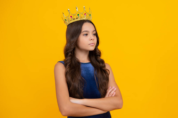 Teenage selfish girl celebrates success victory. Teen child in queen crown isolated on yellow background. Princess girl in tiara. Prom party - Foto, Imagem