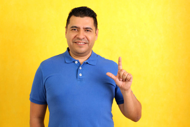 Темноволосый латиноамериканец использует язык жестов, характерный для глухих людей, чтобы создать канал общения с социальной средой. - Фото, изображение