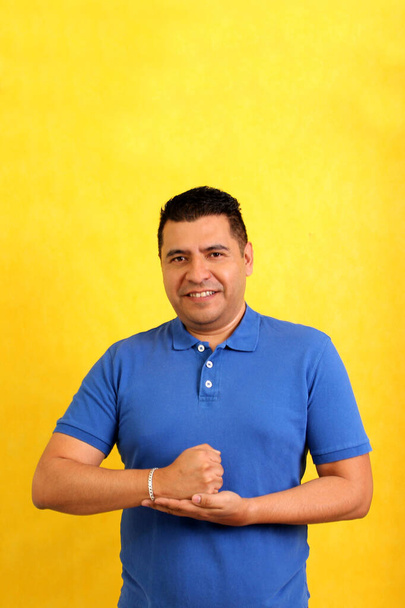 Dunkelhaariger erwachsener Latino-Mann benutzt die für Gehörlose typische Zeichensprache, um einen Kommunikationskanal mit seinem sozialen Umfeld zu etablieren - Foto, Bild