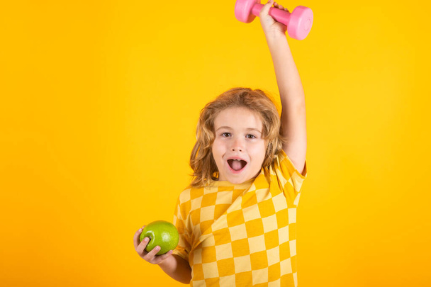 Cute child boy pumping up arm muscles with dumbbell. Fitness kids with dumbbells - 写真・画像