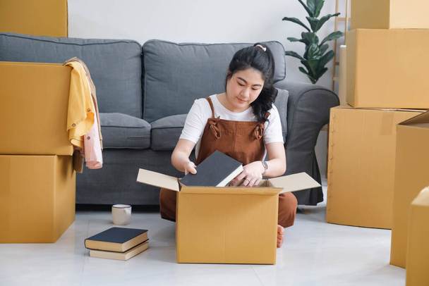 Happy single young woman packing or unpacking cardboard boxes while moving to new house or new apartment. New beginnings emotion. Living alone. Modern female people in moving home apartment leisure indoor activity alone. - Zdjęcie, obraz