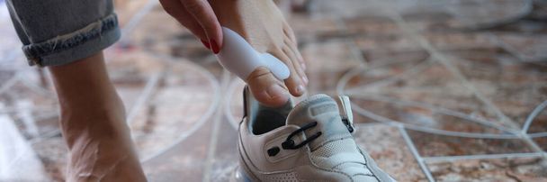 Hallux valgus için destek kullanan ve spor ayakkabı giyen bir kadın. Ayak hastalıkları ve ayak eklemlerinde deformasyon. - Fotoğraf, Görsel