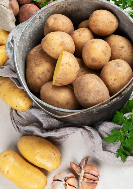 Raw potato food. Fresh potatoes in an old cooking pot on a white background. Top view - Fotografie, Obrázek